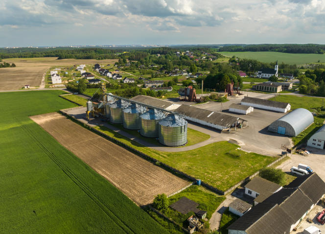 Uma vista aérea de uma fazenda com silos no meio de um campo.