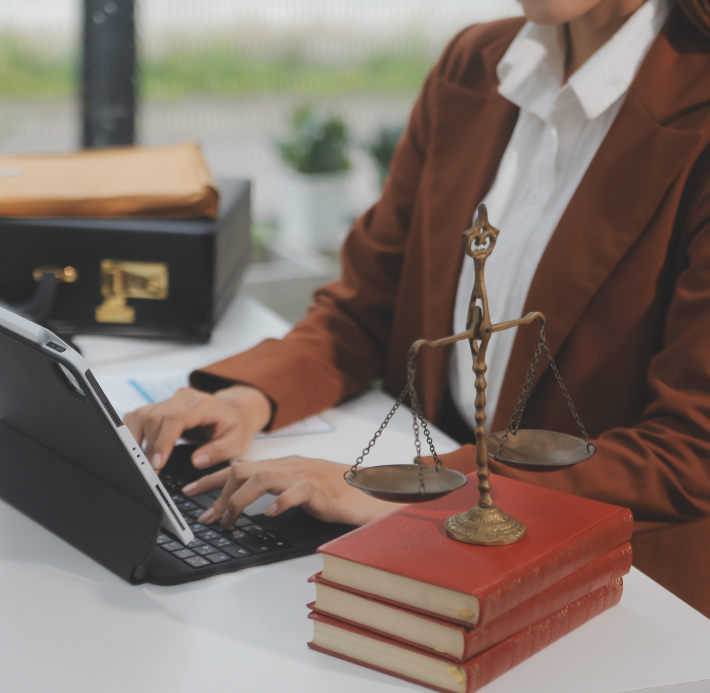 Uma mulher está digitando em um laptop ao lado de uma balança da justiça