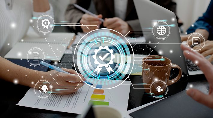 Um grupo de pessoas está sentado ao redor de uma mesa com papéis e um laptop.